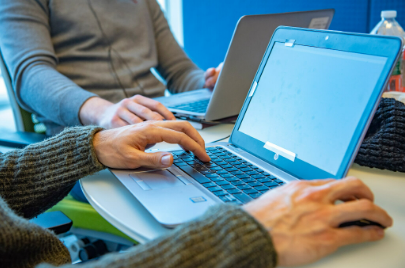 Close-up of a person’s hands using a laptop and mouse.