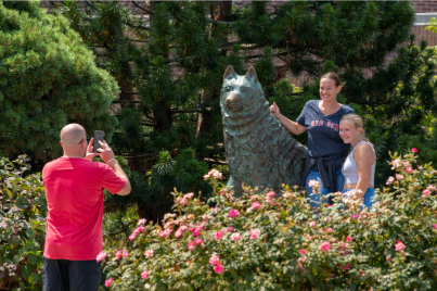 A family taking photos near a statue of Jonathan Husky.
